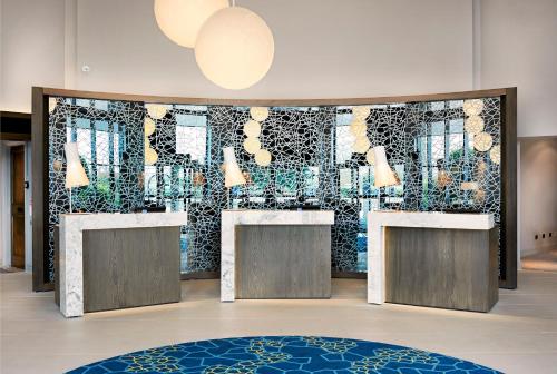 a lobby with a wall of mirrors and counters at Novotel London Stansted Airport in Stansted Mountfitchet