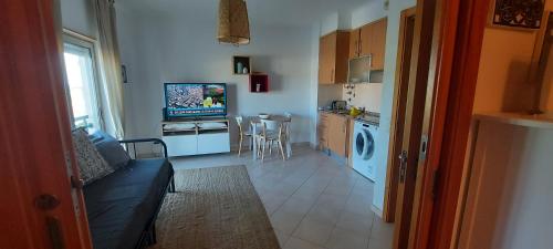 a living room with a couch and a kitchen at Apartamento piscina 5 minutos praia in Alcantarilha