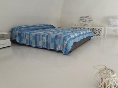 un letto in una camera bianca con coperta blu di Casa Vacanze Le Palette - Glicine a Ponza