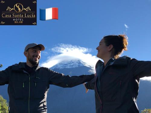 a man and a woman standing in front of a mountain at Hotel Casa Santa Lucía in Baños