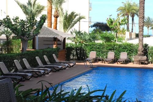 una piscina con tumbonas junto a un complejo en Hotel Los Robles, en Gandía