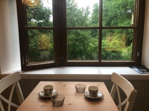 une table avec trois tasses devant une fenêtre dans l'établissement Mathildedal Private Apartments, à Matildedal