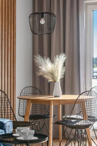 a dining room with a table with chairs and a vase with feathers at Apartamenty Statki na Niebie in Rowy