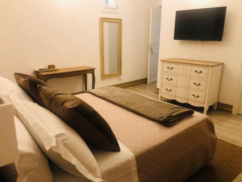 een slaapkamer met een bed, een ladekast en een televisie bij Domus Alberta in Lecce