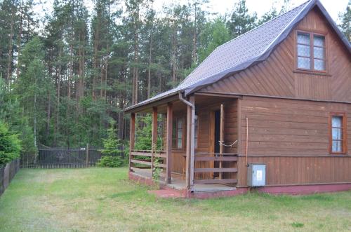 a small wooden cabin with a gambrel roof at Domki Pod Lasem in Macharce
