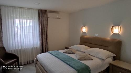 a bedroom with a bed with two pillows and a window at Plitvice Inn in Jezerce