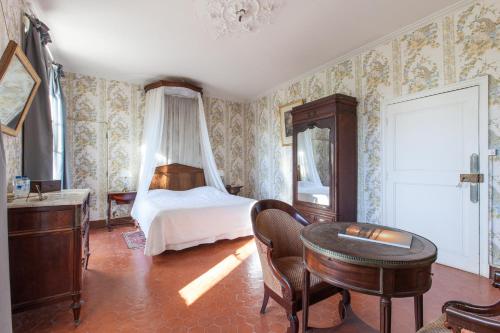 a bedroom with a bed and a desk and a table at Chateau de Saint Martin in Taradeau