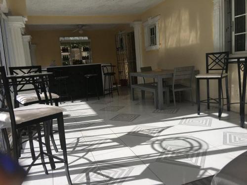 a room with tables and chairs and shadows on the floor at Arms of Charms Guesthouse in Sandy Bay