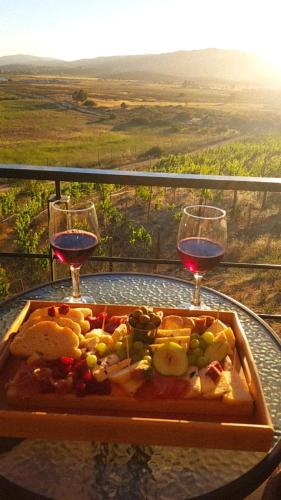 a tray of food on a table with two glasses of wine at Siempre Valle Hotel Boutique in Valle de Guadalupe
