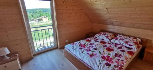 1 dormitorio con cama y ventana grande en Drewniak, en Wisełka