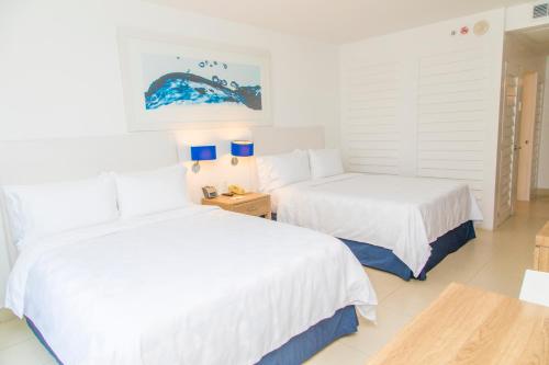 2 Betten in einem Zimmer mit weißen Wänden und blauen Lampen in der Unterkunft Holiday Inn Acapulco La Isla, an IHG Hotel in Acapulco