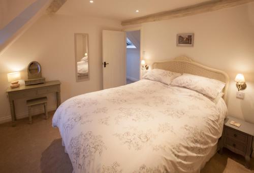 a bedroom with a large white bed and a table at Hook Cottage in Chipping Campden