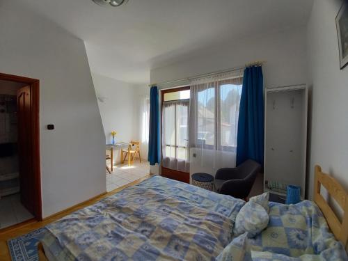 a bedroom with a bed and a chair and a window at Kispál Apartmanház in Zalakaros