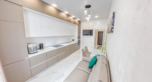 a kitchen with white cabinets and a couch at PEARL PREMIUM APARTMENTS 2 in Kyiv