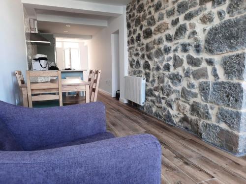 a living room with a blue couch and a stone wall at Apartamentos El Muelle Comillas in Comillas