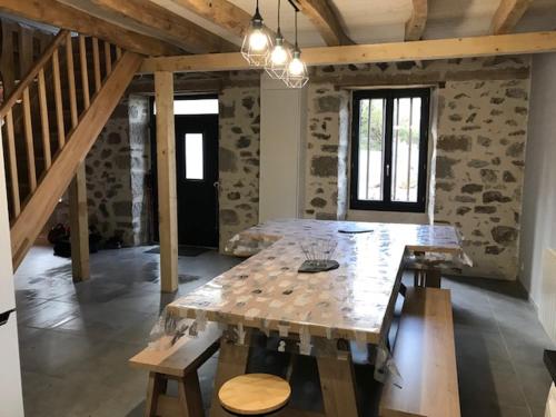 Cette chambre dispose d'une grande table en bois et d'un mur en pierre. dans l'établissement GITE pour famille, à Saint-Clément