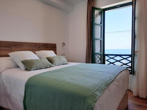 una camera da letto con un grande letto con una grande finestra di Apartamentos El Muelle Comillas a Comillas