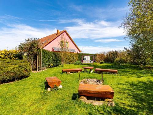 a group of benches sitting in the grass in front of a house at Authentic and cosy holidayhome with big beautifull garden in Altentreptow