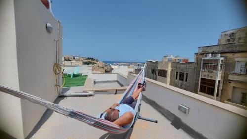 a man laying in a hammock on a balcony at Gunlayer apartments - Flat 3 in Il-Furjana