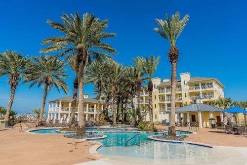 a resort with palm trees in front of a building at Beautiful two-bedroom with bay views in the lovely Pointe West Resort in Galveston