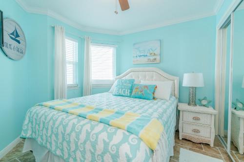Schlafzimmer mit blauen Wänden und einem Bett mit weißer Tagesdecke in der Unterkunft Steps to Pool and BeachAmazing Views from Two Balconies in Galveston