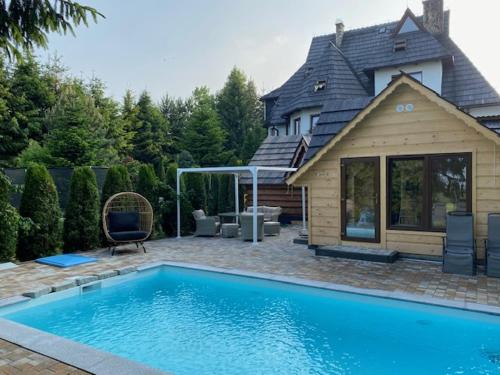 a swimming pool in front of a house at Villa Bialka & Spa in Groń