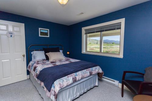 a blue bedroom with a bed and a window at Overlander B&B in Kamloops