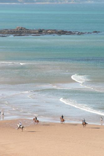 a group of people riding horses on the beach at Carlina Lodge in Biarritz