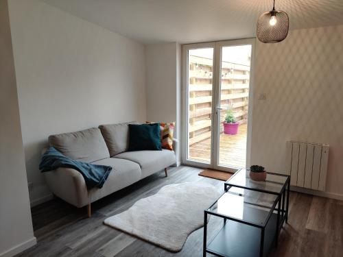 a living room with a couch and a glass table at Joli appartement avec jardin-terrasse privé in Brest