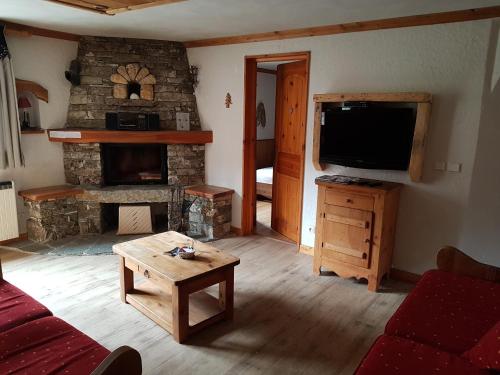 a living room with a tv and a stone fireplace at Chalet l'Avalin in Val dʼIsère