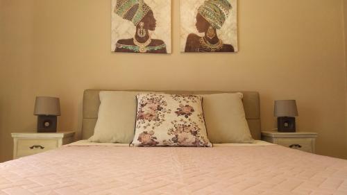 a bed with a pillow and two pictures on the wall at Politakis Apartment in Keramoti