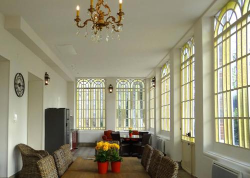a large room with chairs and a chandelier and windows at Bed & Breakfast L'Orangerie in Carcassonne