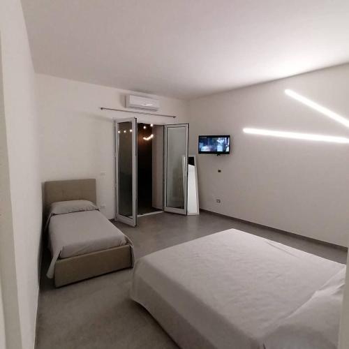 a bedroom with two beds and a flat screen tv at Dimora Felline in Giurdignano