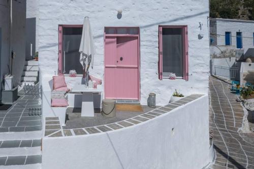 a white building with a pink door and a table at Stella's House in Kimolos