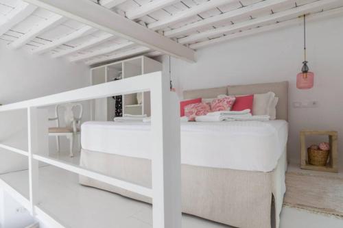 a white bedroom with two beds and a staircase at Stella's House in Kimolos