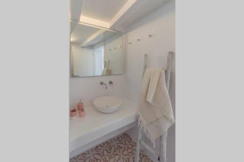 a white bathroom with a sink and a mirror at Stella's House in Kimolos