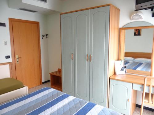 a bedroom with a cabinet and a bed and a desk at Hotel Aquila D'Oro in Misano Adriatico