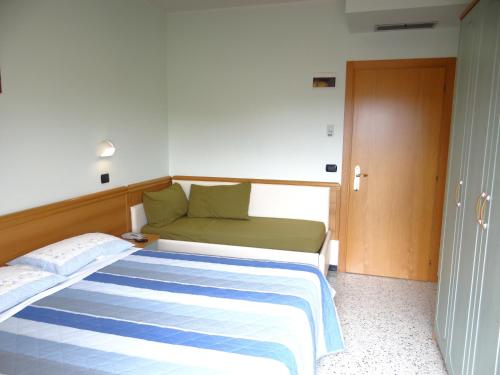 a bedroom with a bed with a green and blue blanket at Hotel Aquila D'Oro in Misano Adriatico