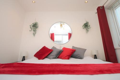 Un dormitorio con una cama con almohadas rojas y un espejo. en Northcote Lane Apartments - By Property Promise, en Cardiff