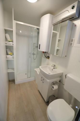 a white bathroom with a toilet and a sink at Floating Sea House SONČEK in Portorož