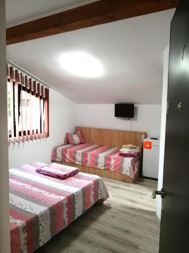 a bedroom with two beds and a flat screen tv at Casa di Sonia in Eforie Nord