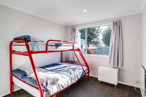 a red bunk bed in a room with a window at SeaRenity - Waimarama Holiday Home in Waimarama