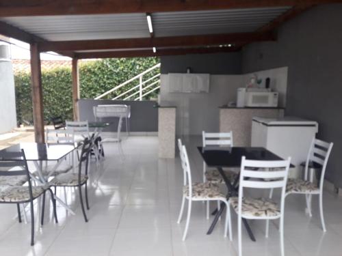 a dining room with tables and chairs and a kitchen at Hospedagem Casa Branca Localizada em um bairro nobre de Capitólio, Escarpas do Lago in Capitólio