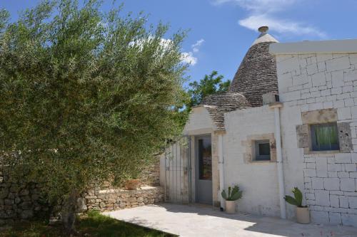 a white house with a tree in front of it at Dimore Barsento in Alberobello