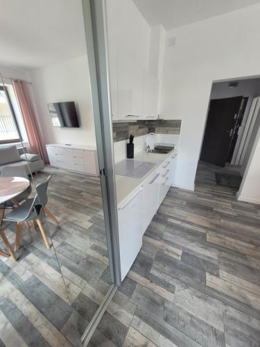a kitchen with white cabinets and a wooden floor at Apartamenty Chopina 1 in Bydgoszcz