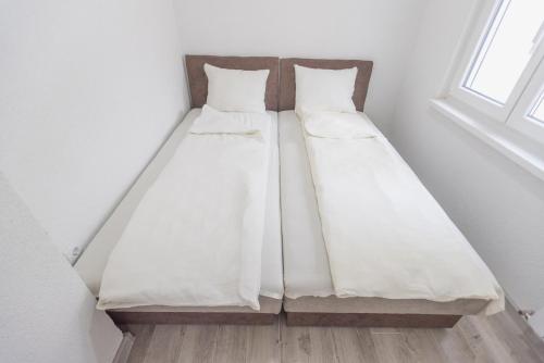 two beds sitting in a room next to a window at Apartmani Centar Loznica in Loznica