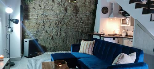 niebieską kanapę w salonie z kamienną ścianą w obiekcie El nido de la Jabonería w mieście Setenil
