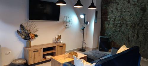 a living room with a couch and a tv on the wall at El nido de la Jabonería in Setenil