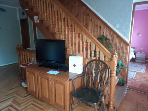 a living room with a tv and a chair and stairs at Milojković in Donji Milanovac