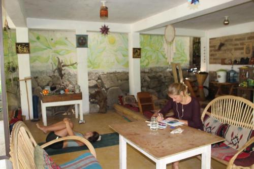 a woman sitting at a table with a dog laying on the floor at Casa AHAU in San Marcos La Laguna